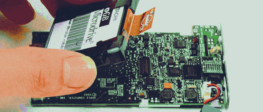 Hard drive being removed from a cracked open iPod Mini